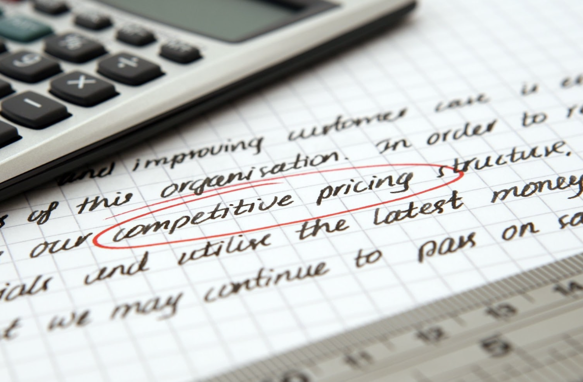 Calculator alongside a piece of paper with the text "competitive pricing" circled