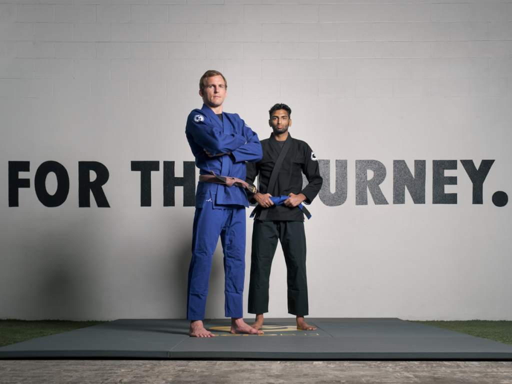 Two JuJitsu instructors standing infront of wall with the text "For The Journey"