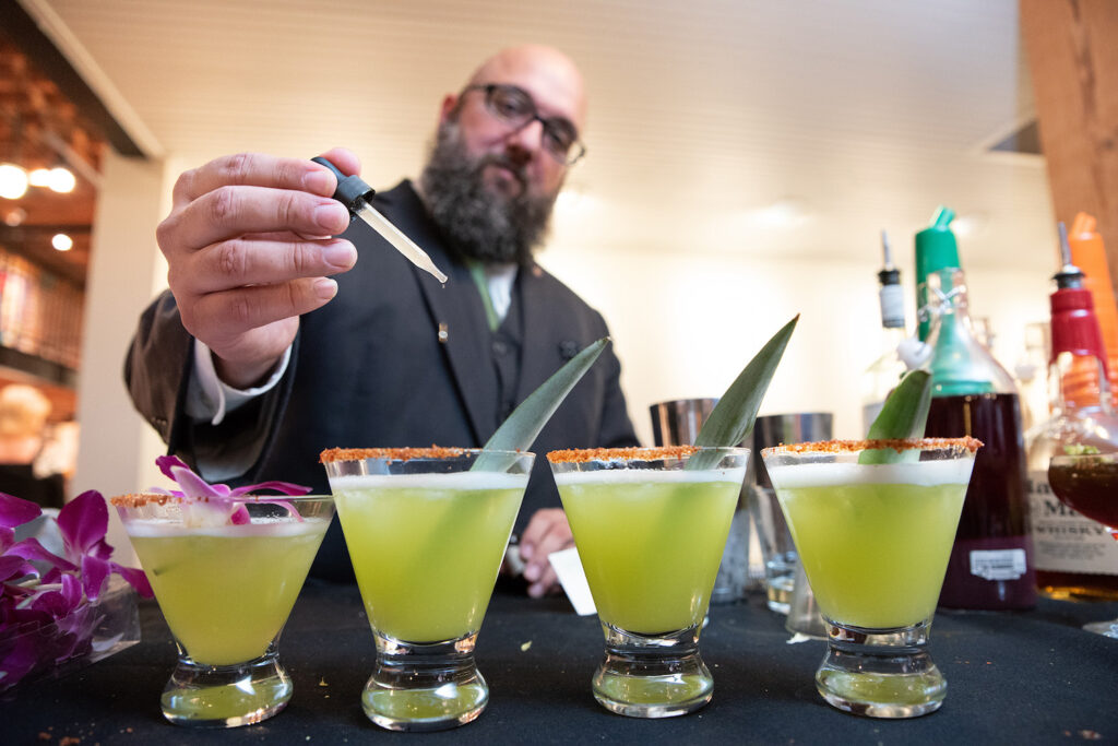 Man adding dropper of flavors into tea drinks at the In Wonderland Tea Tasting Dinner and Art Show