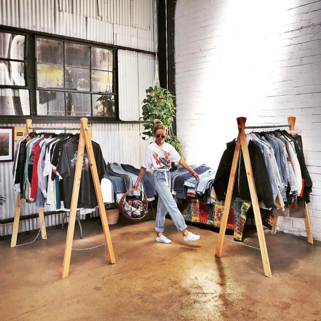 Thrifting pop-up shop owner Michelle Gonzalez of Percy Vibes San Diego in front of racks of clothes