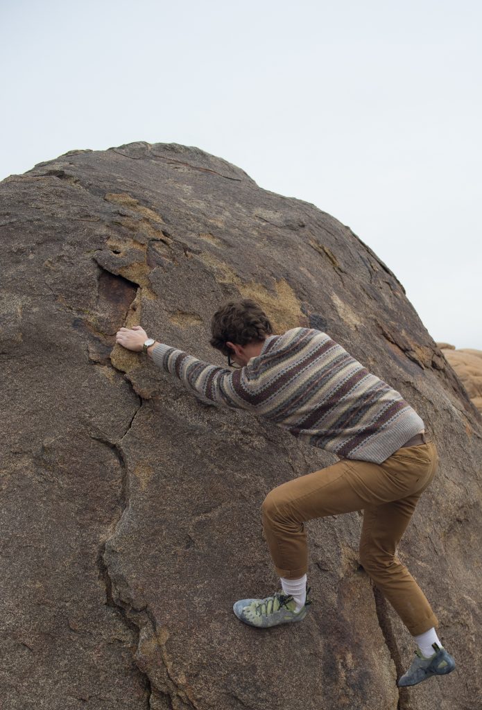 Boulder climber grabbing a hand hold