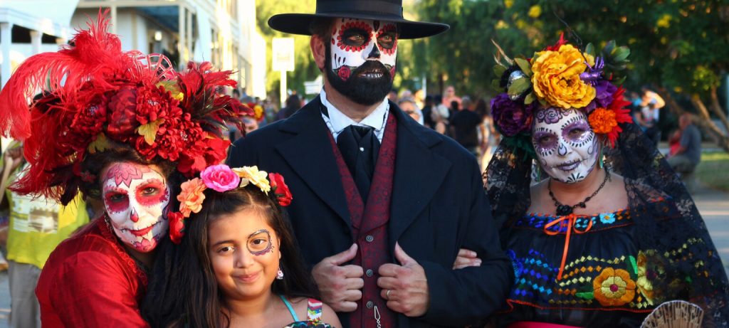 A family dressed in Día de Muertos attire and face painting of the iconic Calavera/sugar skull