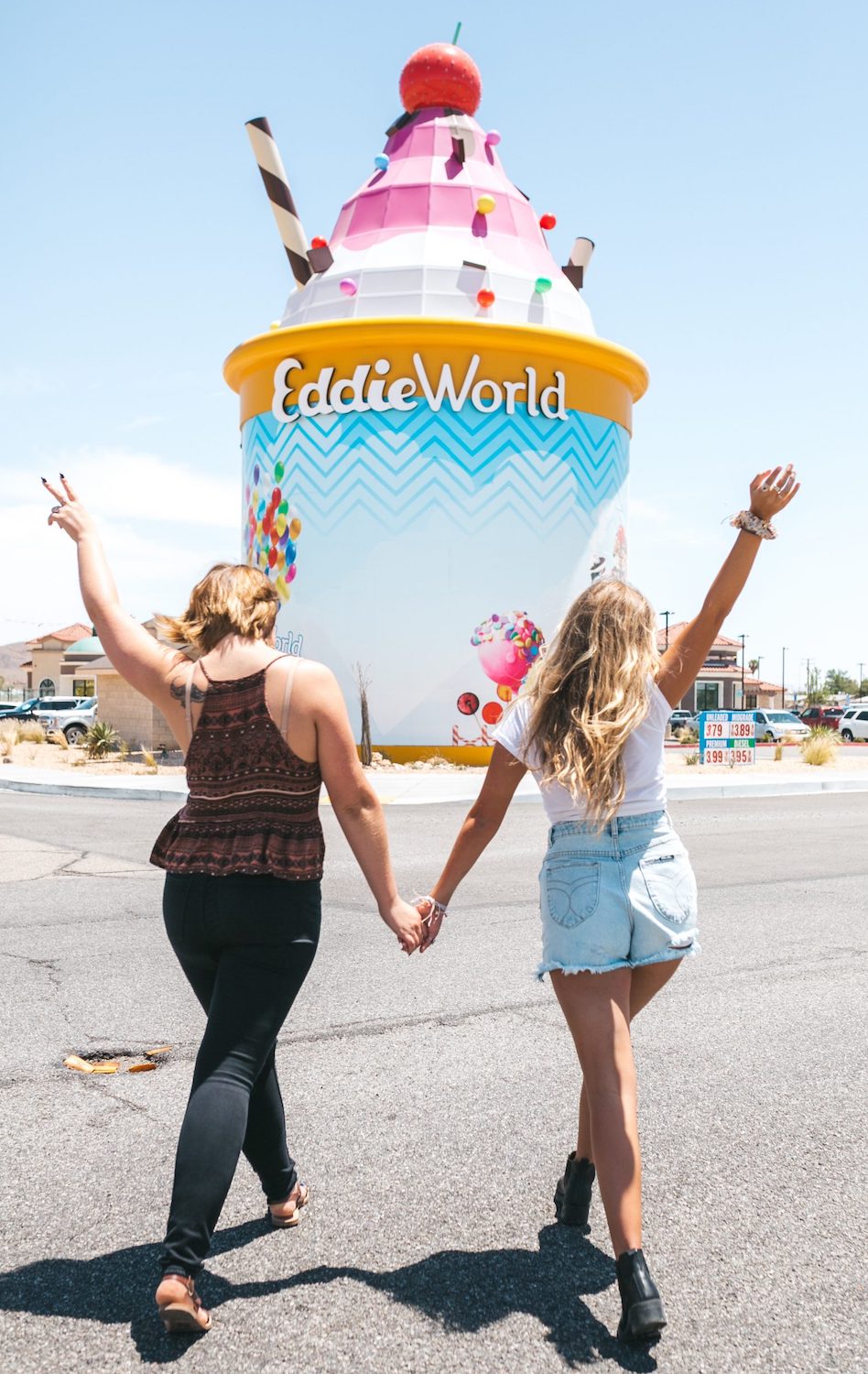 Two girls holding hands walking towards EddieWorld Largest California Gas Station