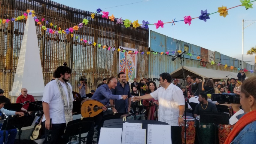 Fandango Fronterizo event at the US Mexico Border with son jarocho musicians shaking hands