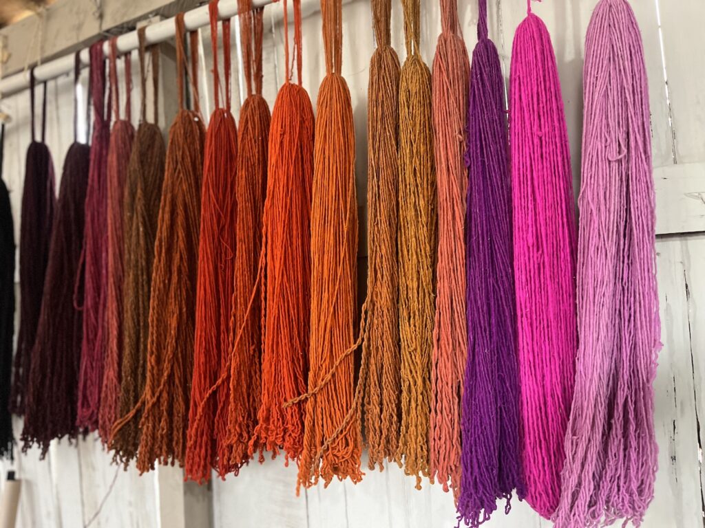 Rows of dyed textile in a row starting with maroon and ending on pink