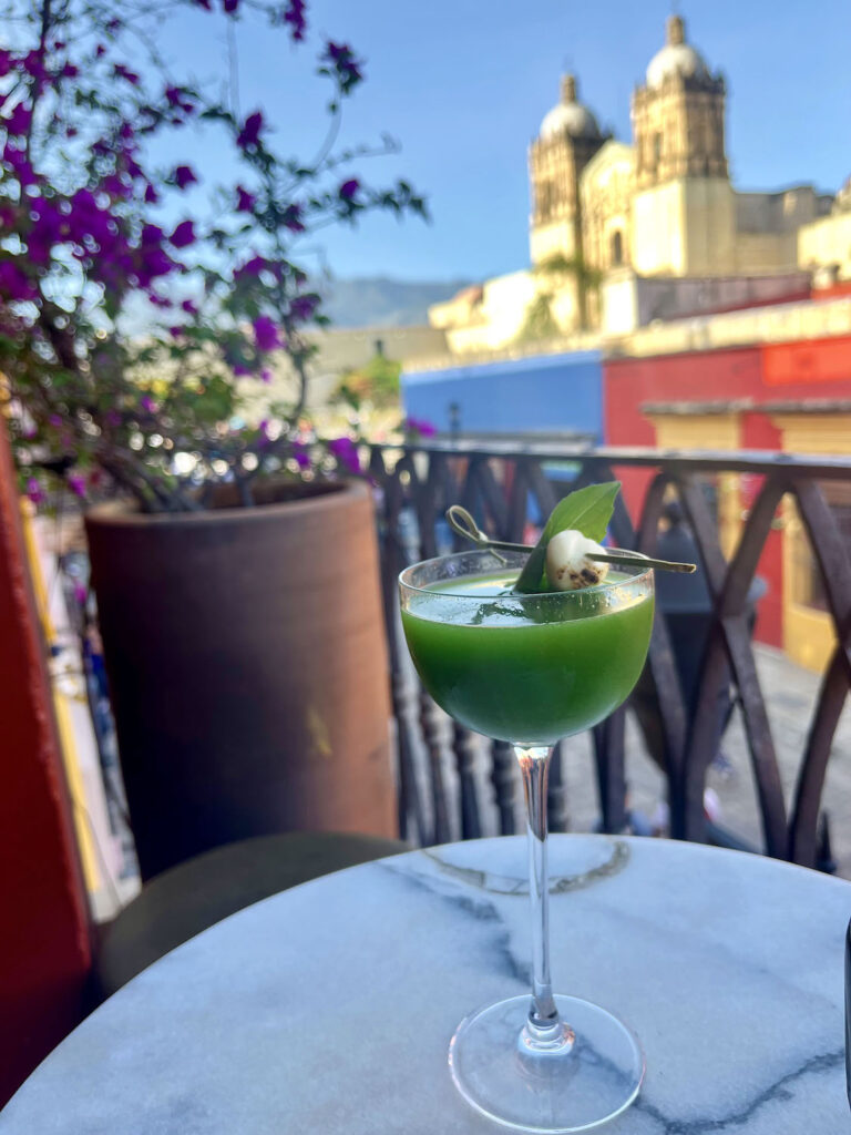 Green colored cocktail at Selva in Oaxaca Mexico featuring a roasted ball of Oaxacan cheese as a garnish