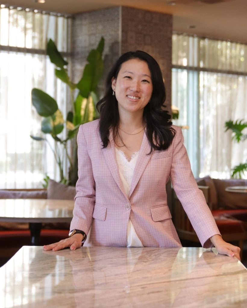 Ann Sim general manager of San Diego restaurant Callie standing infront of a table