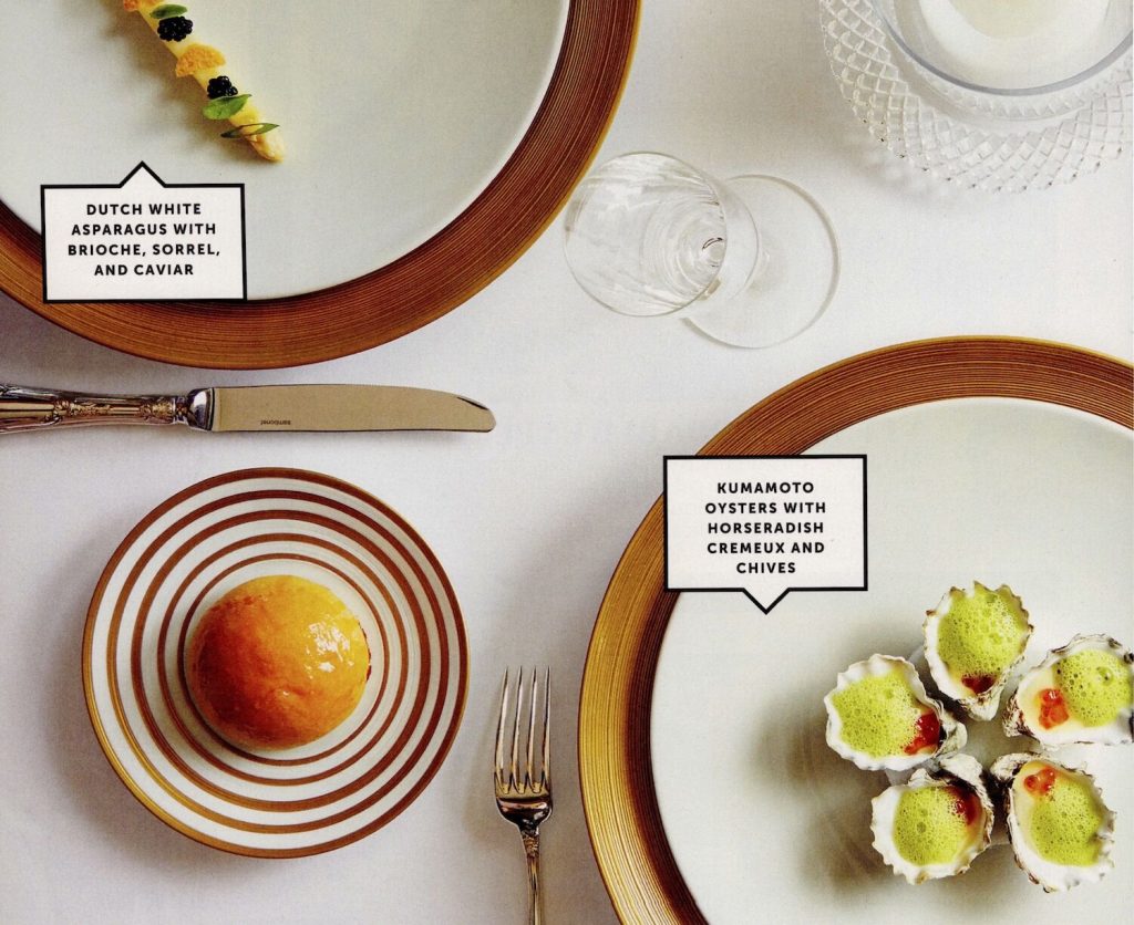 An excerpt from one of San Diego Magazine's food reviews featuring a table set with luxurious dishes and the text "Dutch white asparagus with brioche, sorrel and caviar" and "kumamoto oysters with horseradish cremeux and chives"