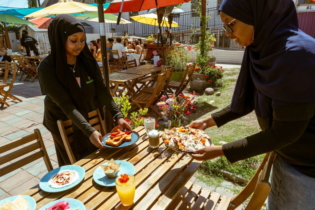 Photo from photographer Cole Novak of Middle Eastern immigrants serving food in traditional attire at San Diego restaurant and garden MAKE Cafe in North Park  