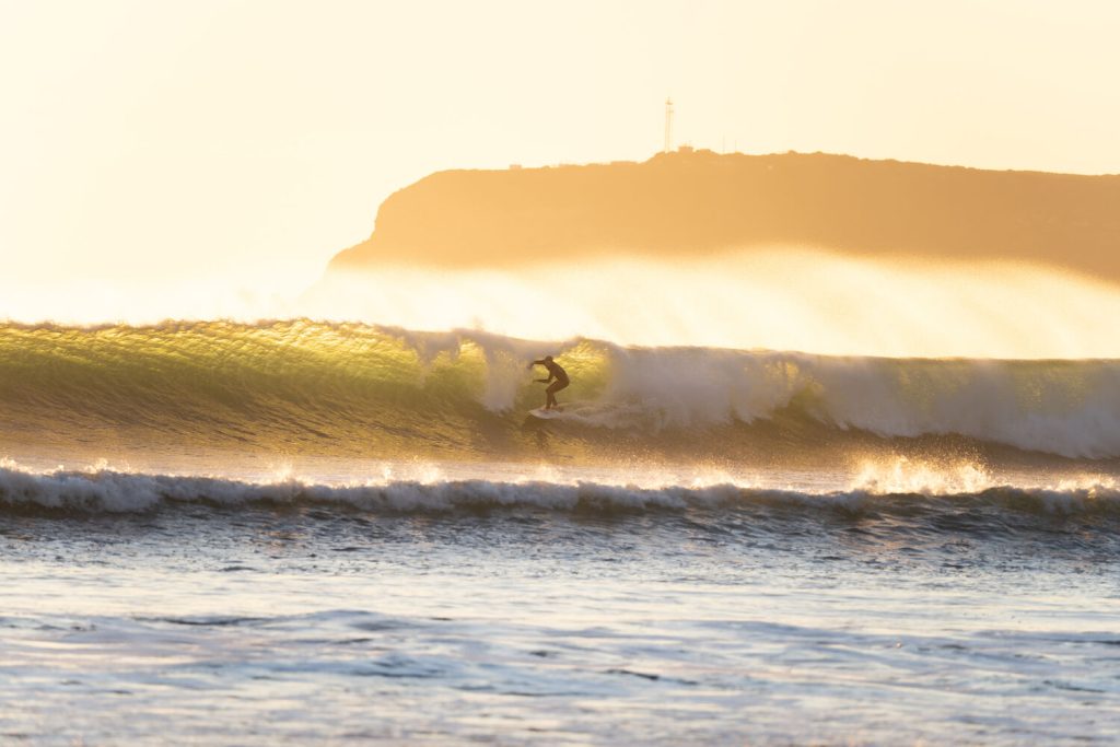 Photo from photographer Cole Novak featuring a surfer on a wave at Coronado Beach at sunset with Point Loma in the background
