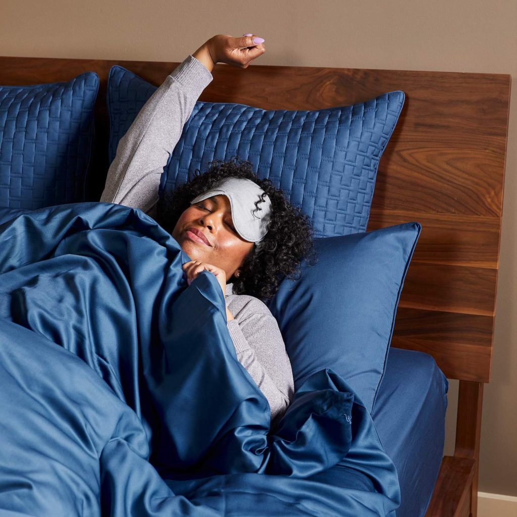 Woman waking up in bed using sheets and attire from Cool-jams