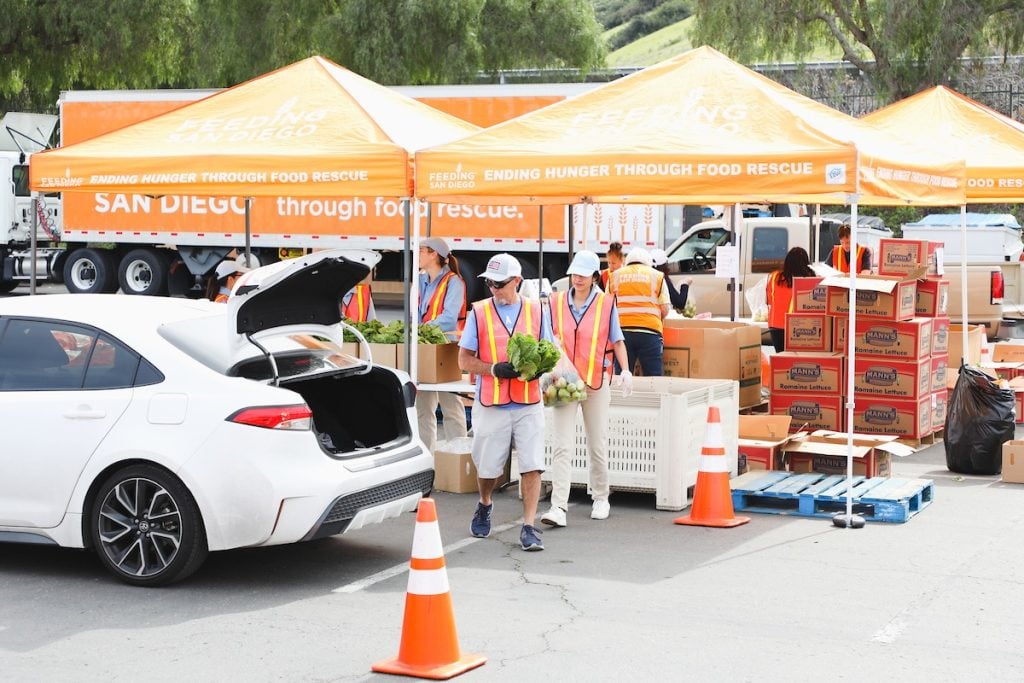 Volunteers from nonprofit Feeding San Diego load food and resources into a recipients car