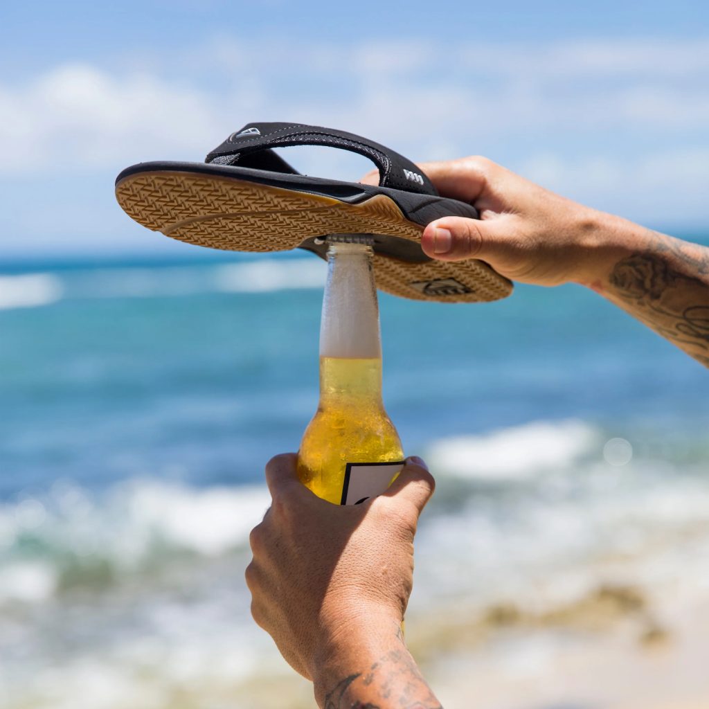 Person opening beer with sandal from San Diego brand Reef