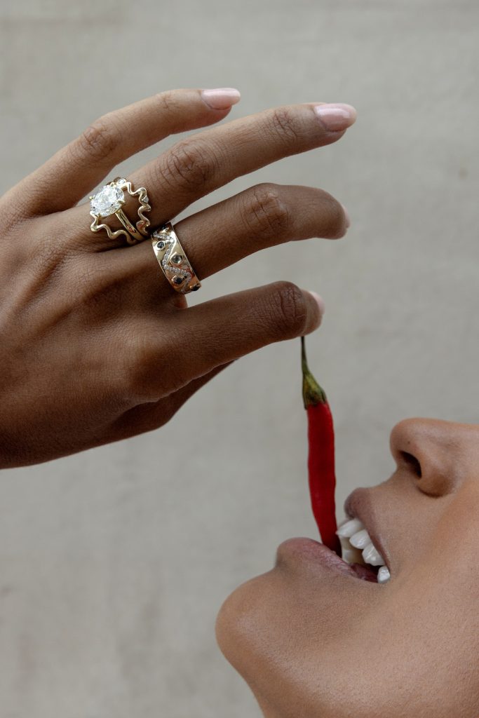 Woman wearing jewelry from San Diego brand, Marrow Fine and Crevette Design Studio while eating a pepper