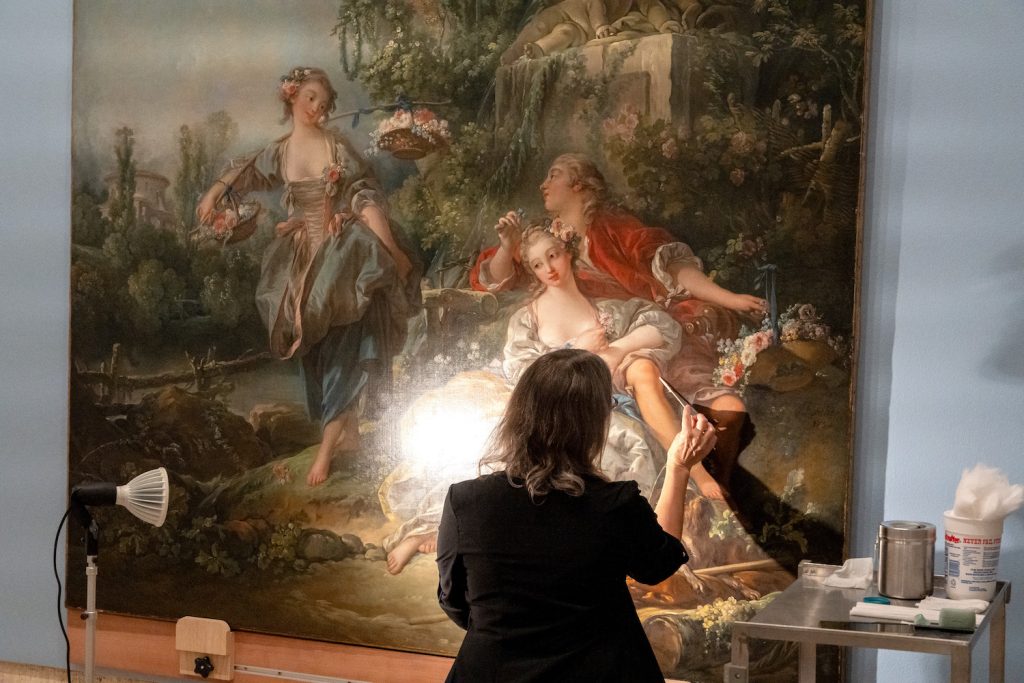 A worker at the Balboa Art Conservatory in San Diego works to restore a 300 year-old oil painting "Lovers in a Park" by Francois Boucher