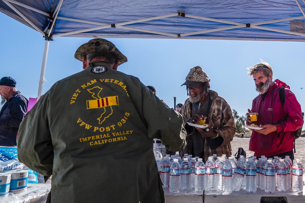 Slab City veterans and other displace individuals queue for a meal at the Stand Up