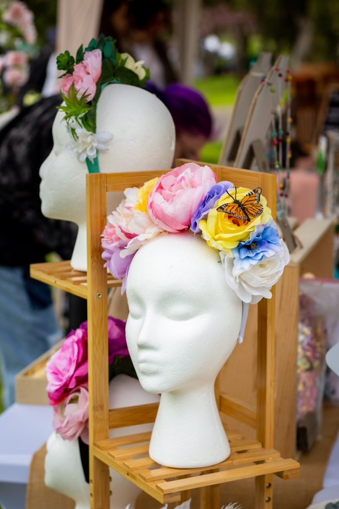 A local vendor selling colorful floral hair bands at the East Village Artisan Market