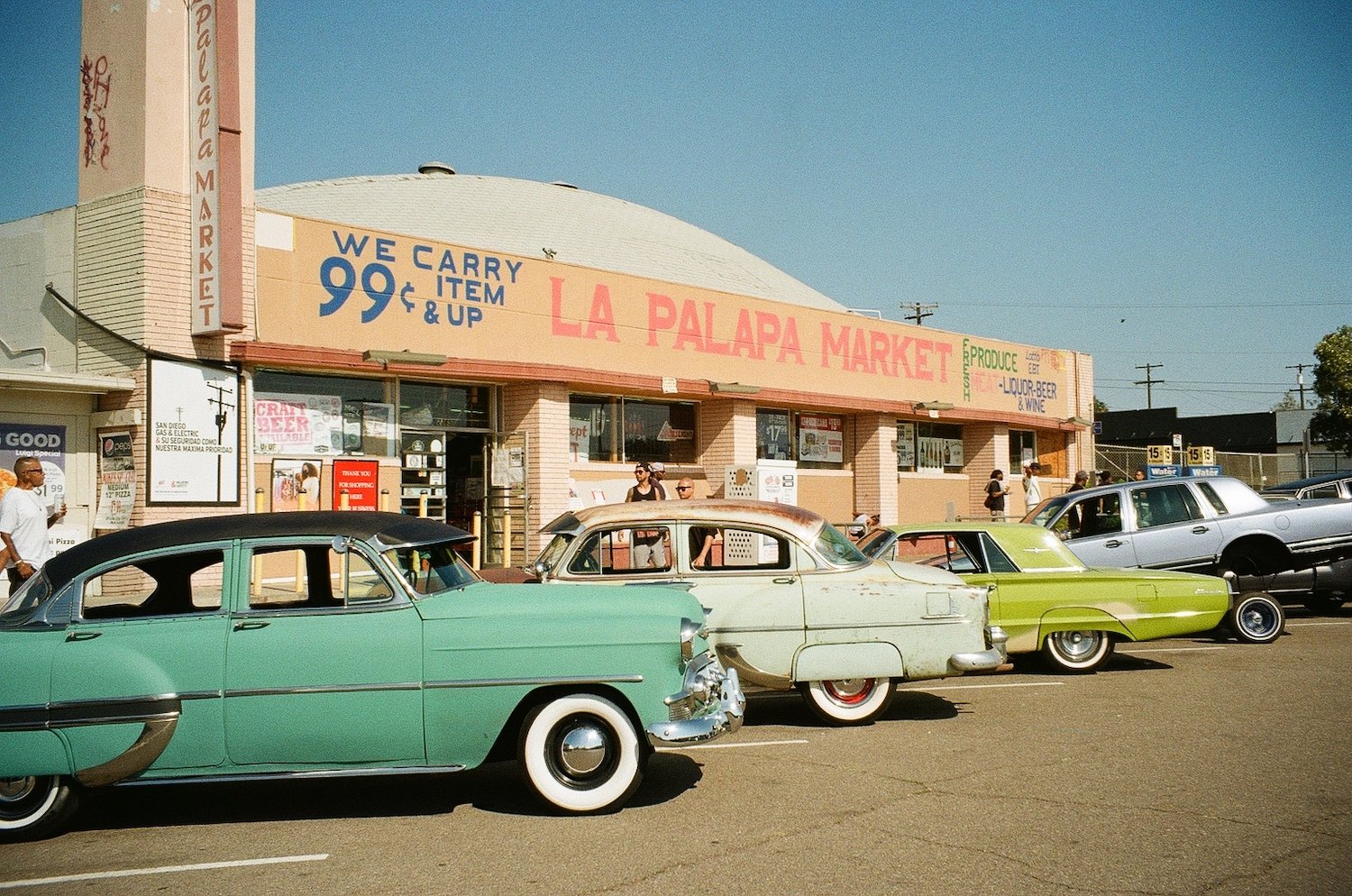 Row of vintage cars and lowriders in front of a market in Paradise Hills, San Diego in the South Bay