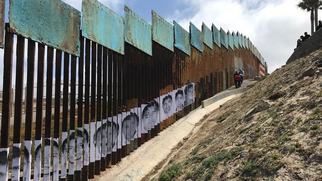 The San Diego Tijuana border wall featuring images of people on the bars of the structure
