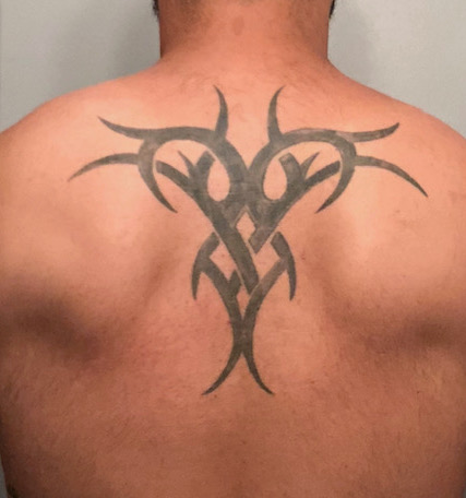 San Diego Magazine's user submitted regrettable tattoos featuring a man's back with a tribal tattoo 