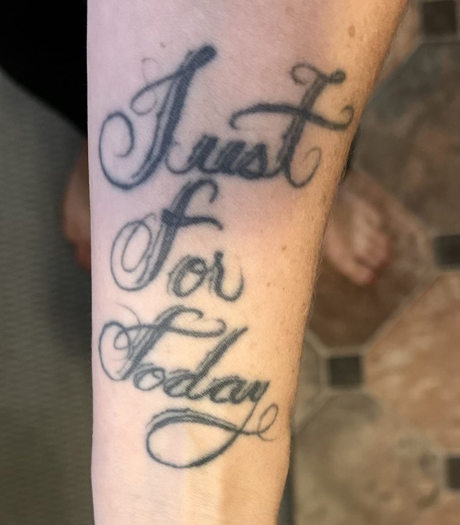 A lady's wrist tattoo featuring the text "Just For Today" in permanent ink