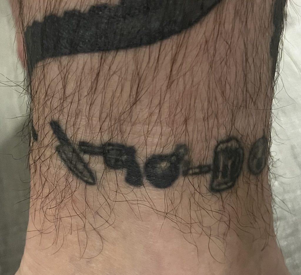 San Diego Magazine's user submitted regrettable tattoos featuring a man's ankle with a set of emojis including a knife, gun, bomb, cigarette, and beer
