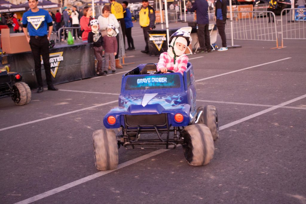 Kid riding a miniature monster truck toy in the parking lot at the Pit Party before the 2024 San Diego Monster Jam