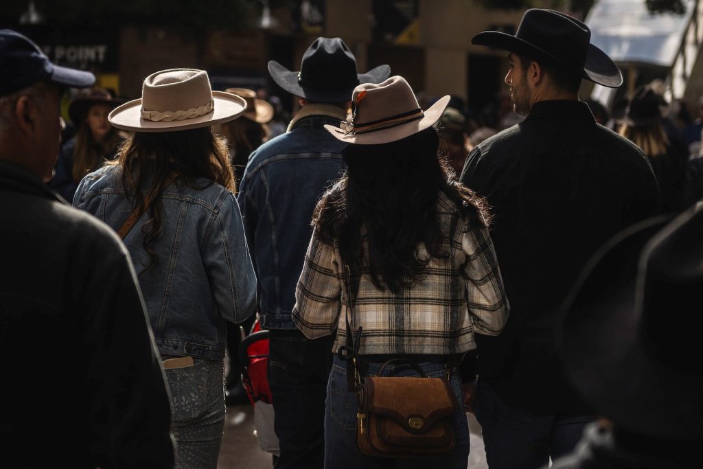 A group of San Diego rodeo attendees walking together in cowboy boots, denim jackets, and hats