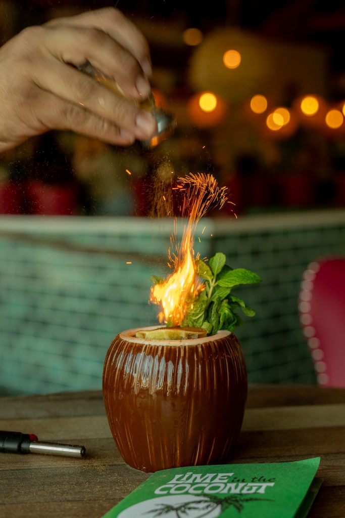 A tiki drink in a coconut cup with a flame on top from Lime in the Coconut in Chula Vista, San Diego 