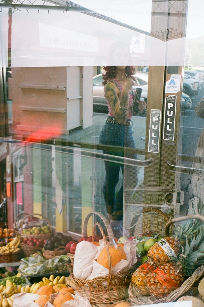 Film photo double exposure of fruit in the window of a South Bay market with a woman in the reflection from 619 Gurlz photographer Delana Delgado