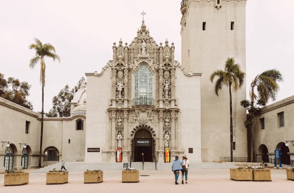 Exterior of the San Diego Museum  of Us featuring two people standing out front at the Prado tower in Balboa Park, San Diego