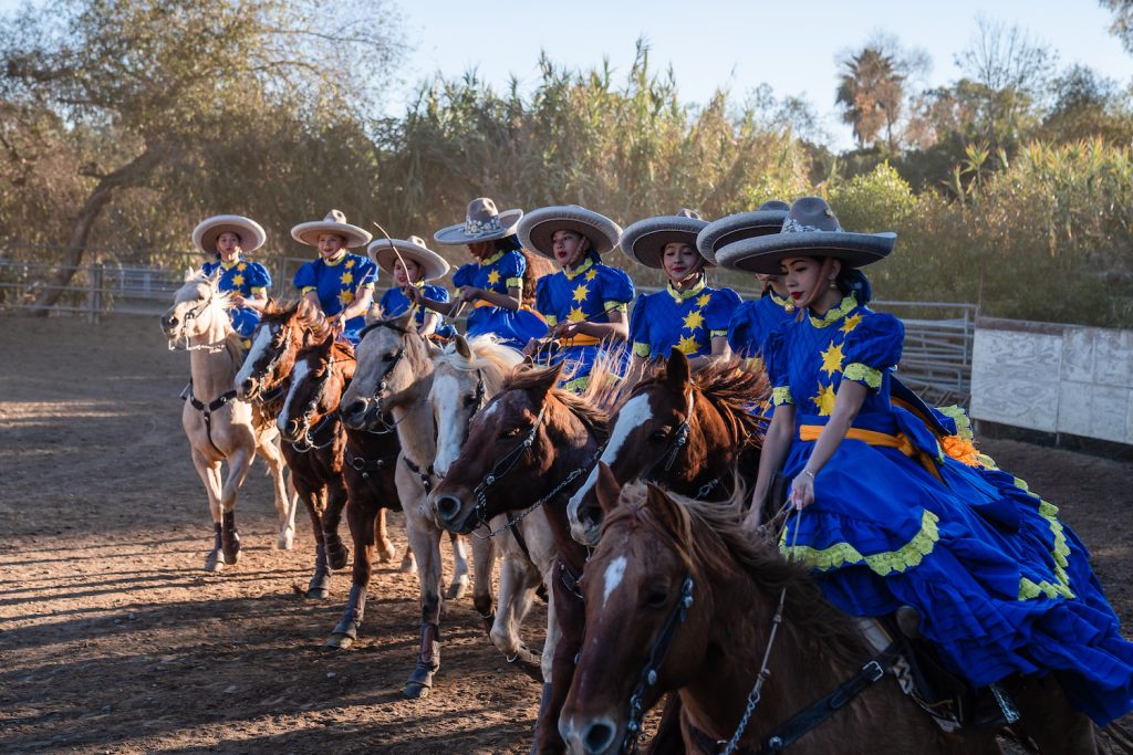 The San Diego Escaramuza team Las Reynas del Sol’s in a traditional Mexican dresses atop each of their horses