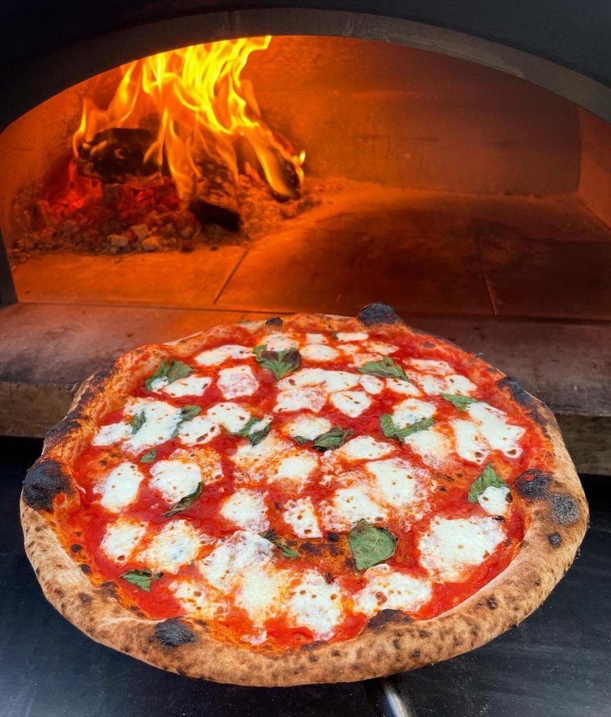 A margarita pizza going into an over from Yuma, Arizona's Ellie's Wood Fired Pizza which is relocating to Ocean Beach, San Diego 