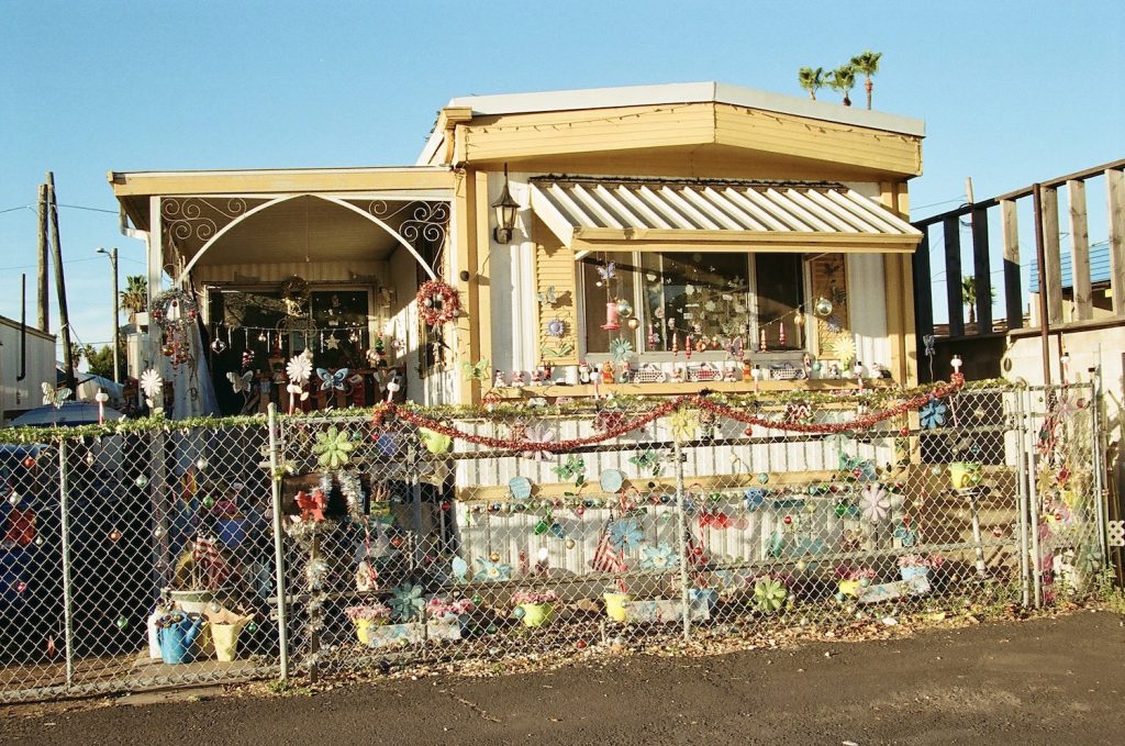 Film photo of a South Bay trailer home with trinkets and collectibles in their yard by 619 Gurlz photographer Delana Delgado