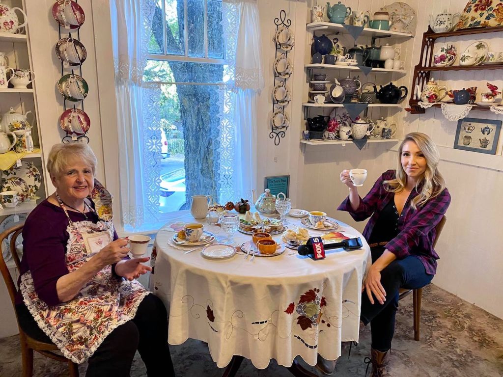 Two women sitting at an antique tea table surrounded by teapots at Julian Tea & Cottage Arts in Julian, San Diego 