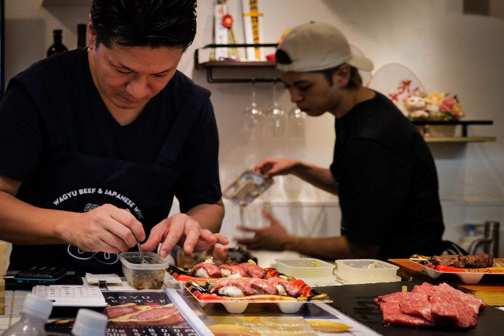 Chefs at Wagyu 88 preparing and cooking Wagyu nigiri at the restaurant in Tokyo, Japan