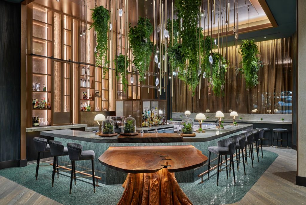 Interior of the Ritz-Carlton Portland, Oregon hotel featuring their Meadowrue lobby bar full of plants and cedar trunk furniture, one of Oregon's most popular new hotels to visit in 2024