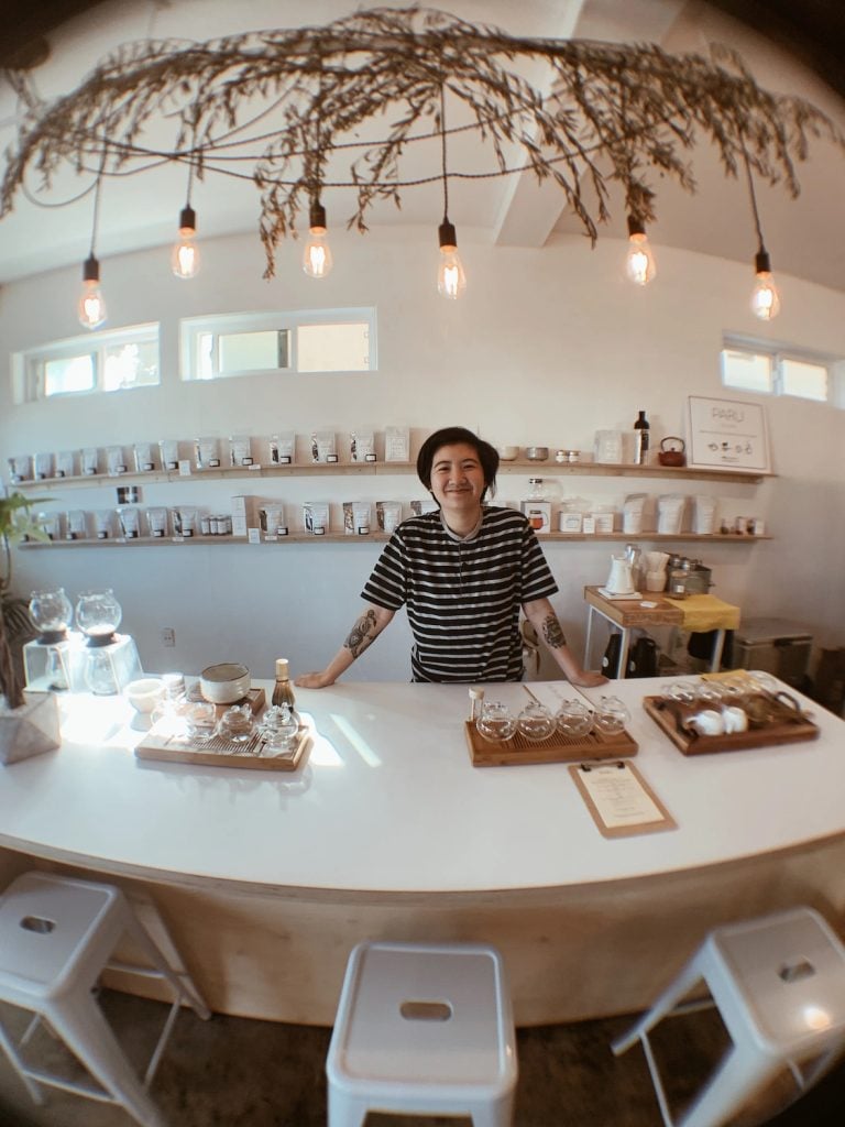 Interior of PARU Tea in Point Loma featuring the owner standing at a white table with his tea making pots and glass equipment