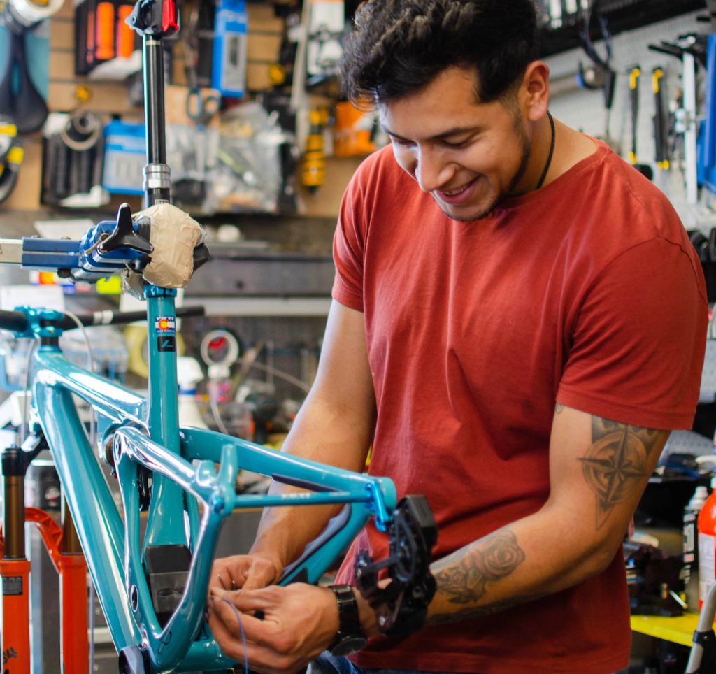 South Bay bike and coffee shop Peninsula Bikes located in San Ysidro, San Diego featuring a worker repairing a light bicycle  