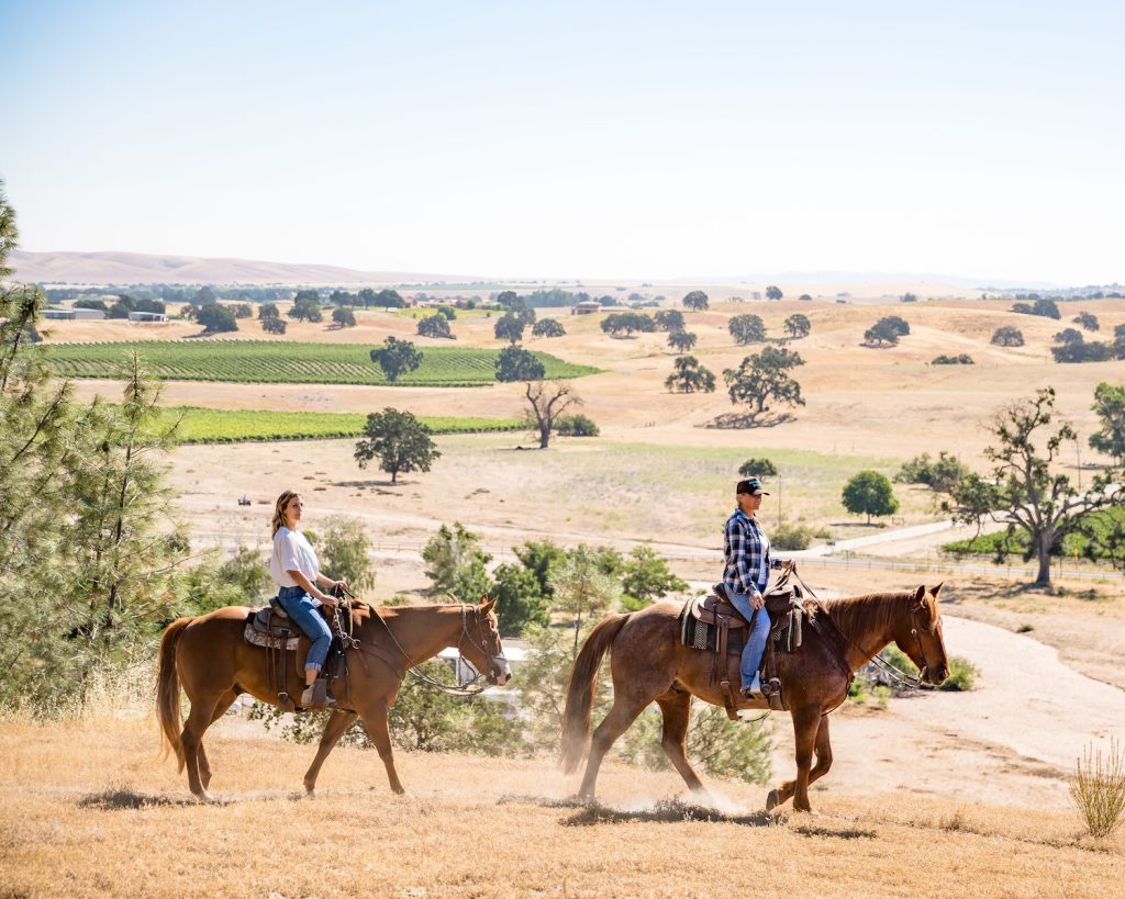 A man and a woman riding horses through the valleys of Paso Robles, California with Central Coast Trailrides