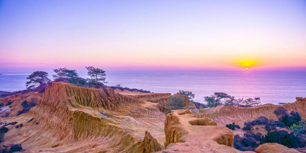 Torrey Pines State Natural Reserve, featuring a view of the cliff rock formations with a purple sunset in the background