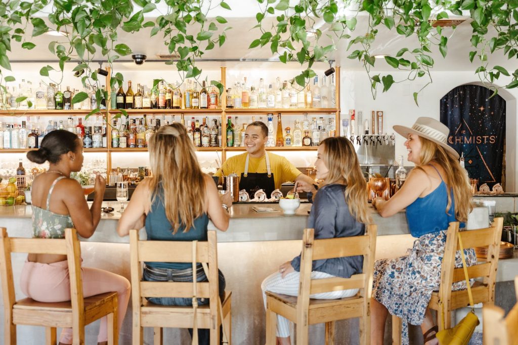 Interior of The Alchemists' Garden cocktail bar with four women sitting at the bar talking to the bartender in Paso Robles, California 