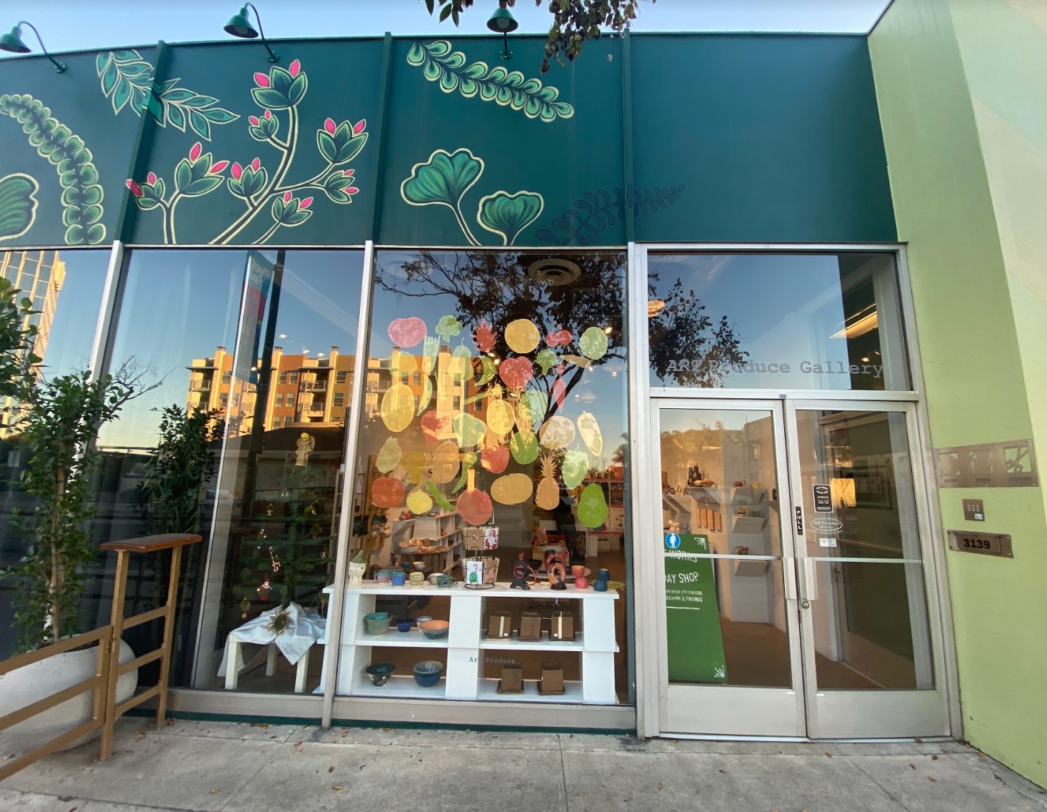 Exterior of Art Produce art gallery in North Park featuring large glass windows and plant murals on the walls
