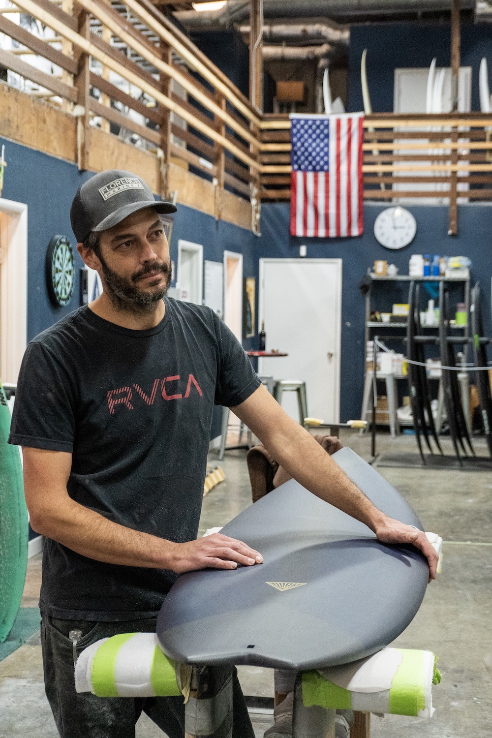 Dark Arts Surfboards founder Justin Ternes holding a carbon fiber surfboard inside his Barrio Logan factory in San Diego 