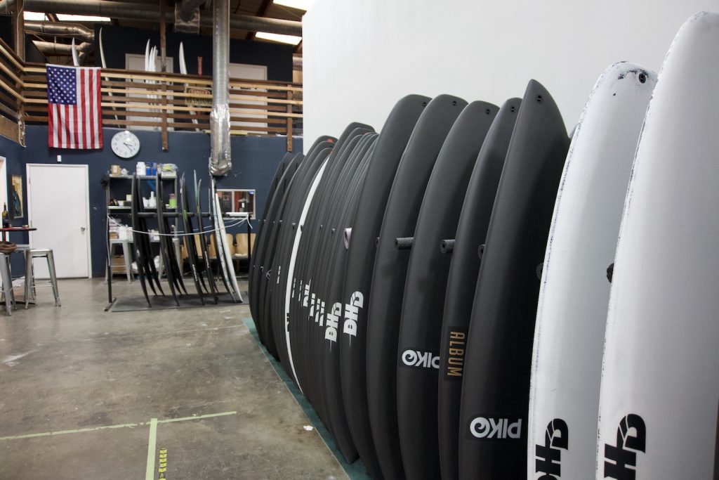 Interior of the Dark Arts surfboards Barrio Logan factory featuring a row of black surfboards