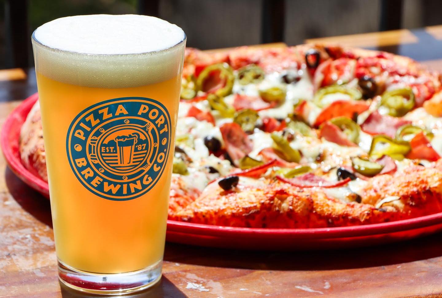Pizza Port Brewing Company's new location at Belmont Park, San Diego featuring a glass of beer and a pizza