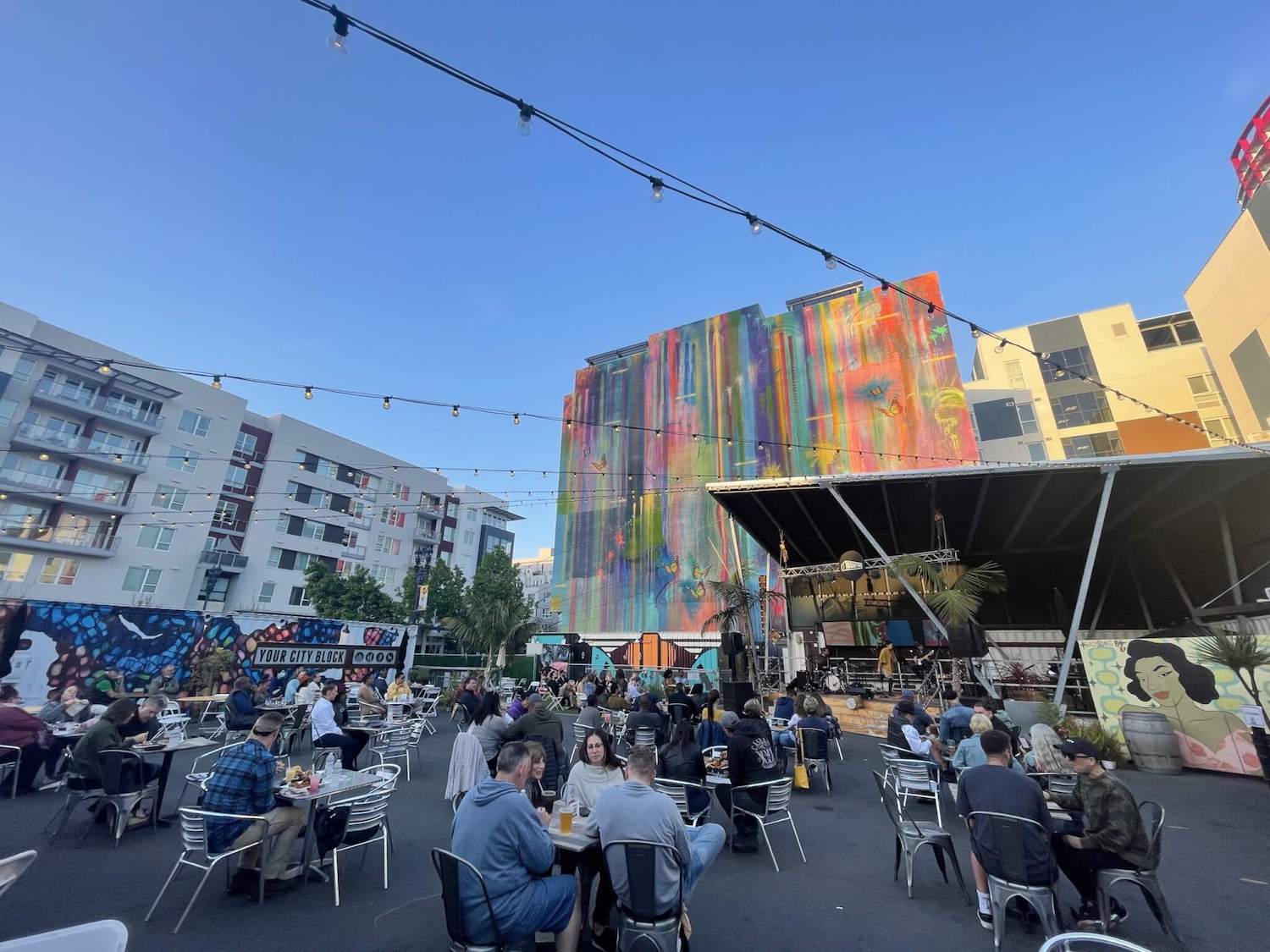 Interior of the Quartyard concert venue and event space in East Village, San Diego featuring patrons eating in front of a stage outside