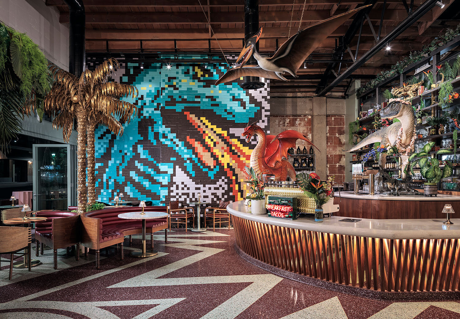 Interior of The Invigatorium brewery and bar in East Village, San Diego featuring a colorful bar full of life-size dinosaur statues