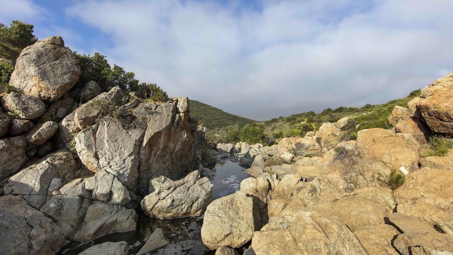 Hike at Los Penasquitos Canyon Trail near Mira Mesa featuring boulders up surrounding a stream at the top of the mountain