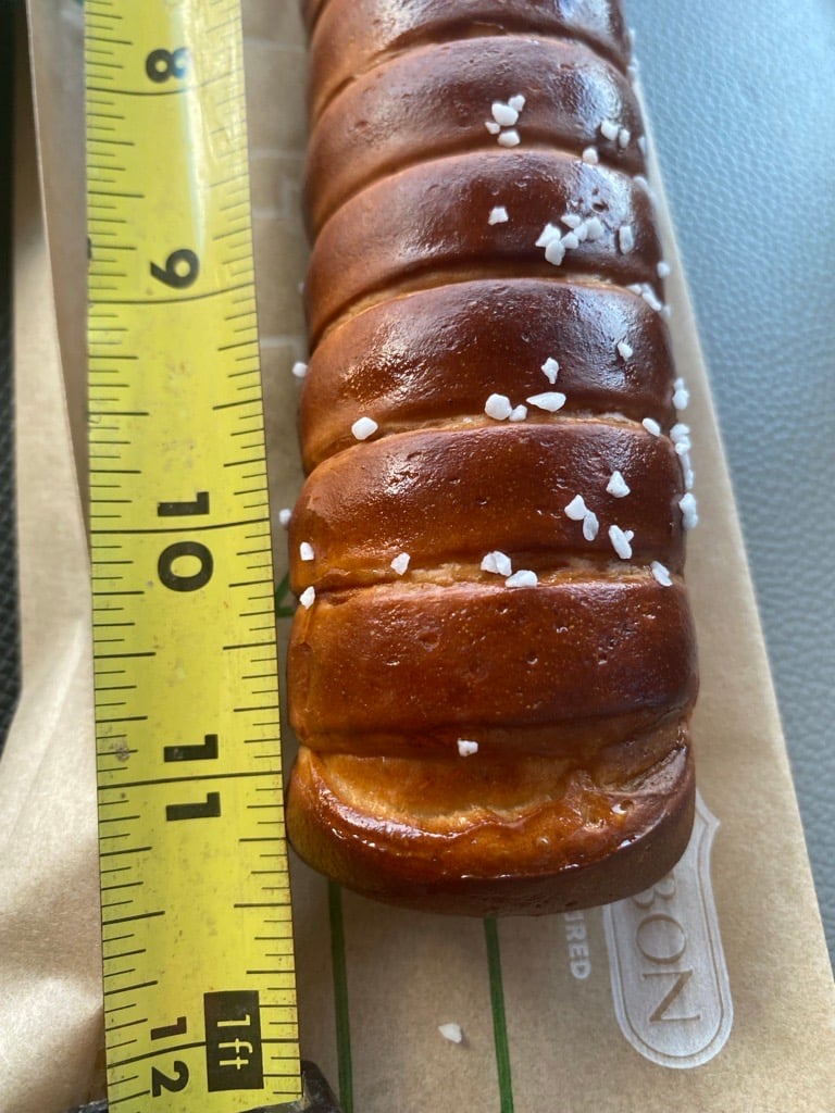 Subway's new Auntie Anne's footlong pretzel bread next to a tape measure indicating it is not 12 inches long